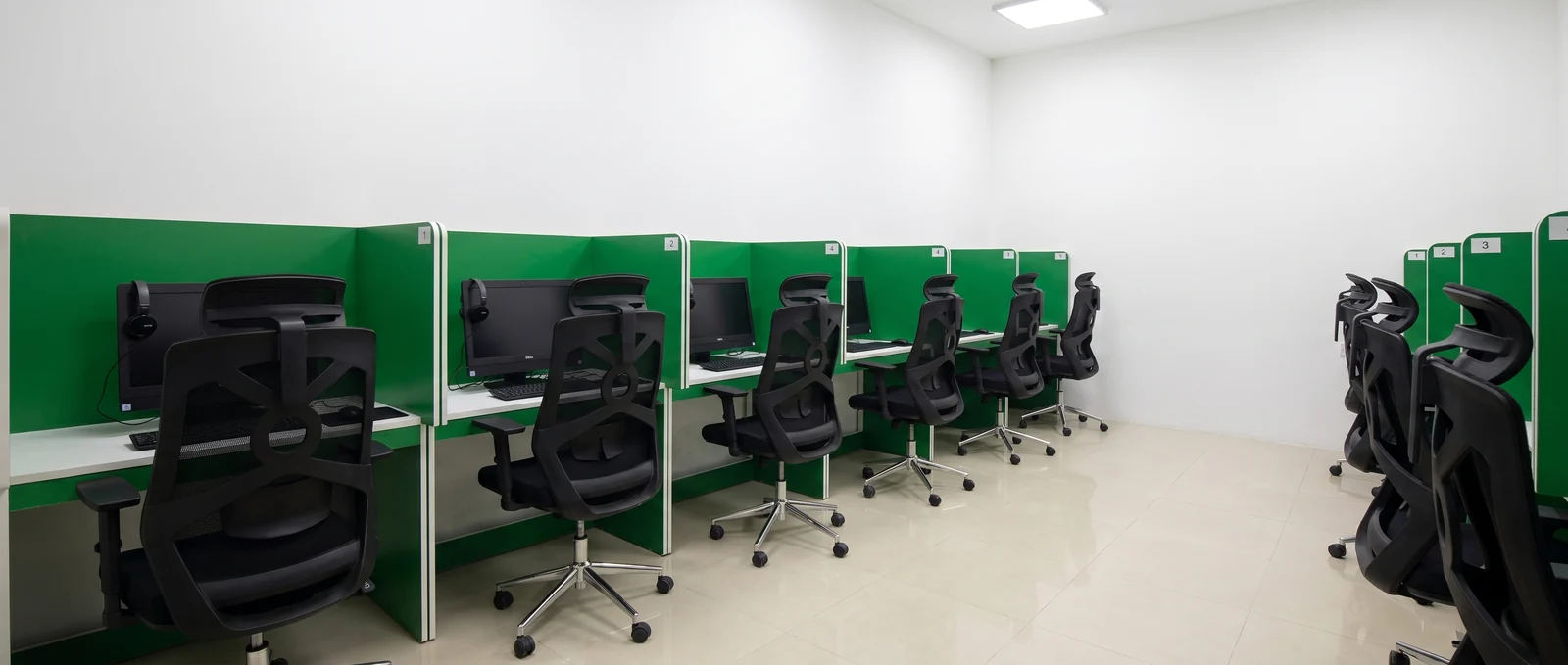 English World's computer-based IELTS testing room — private booths with monitors, keyboards and ergonomic chairs